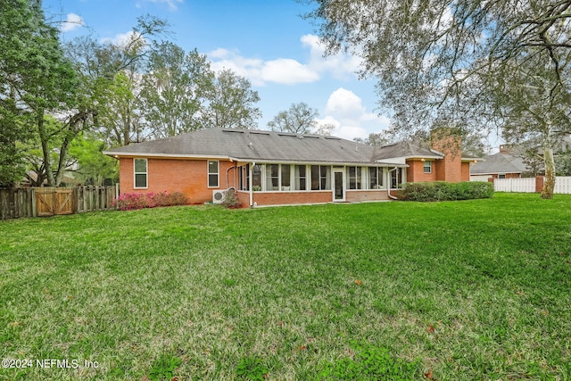 back of property with a yard and a sunroom