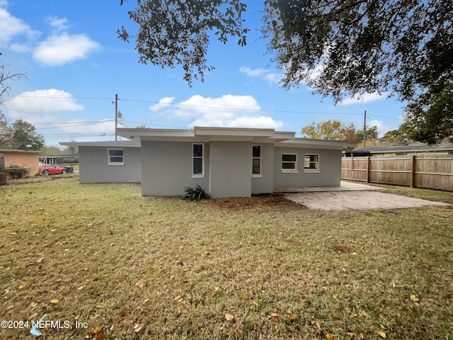 back of property with a lawn and a patio