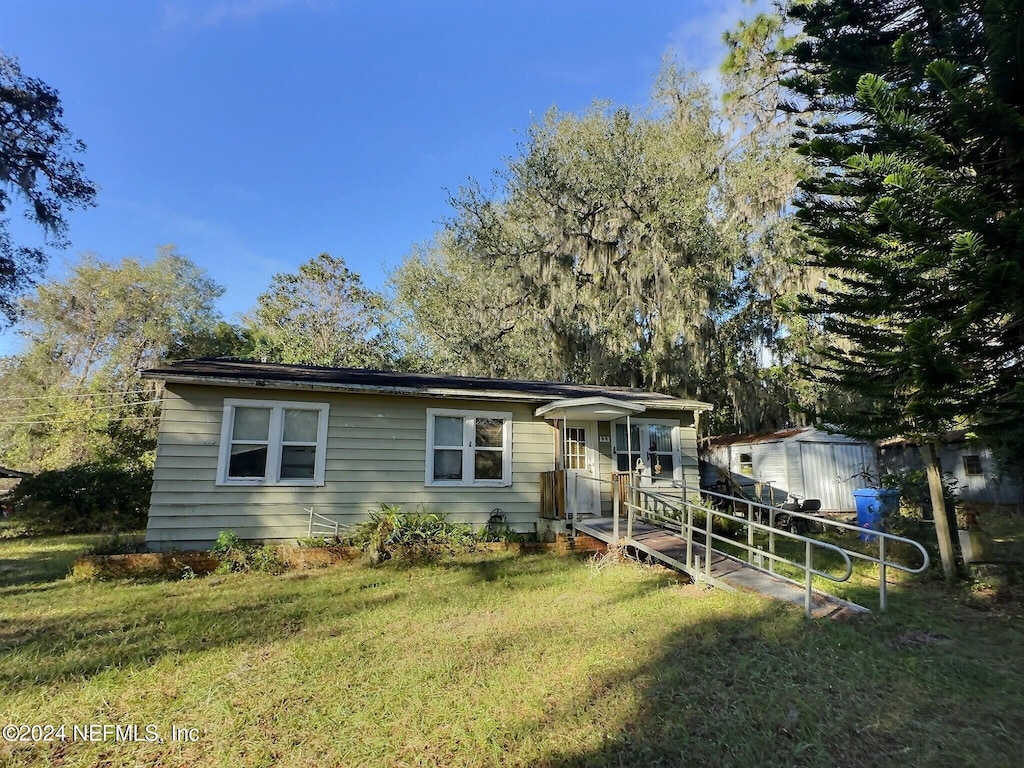 view of front of house featuring a front lawn and a storage shed