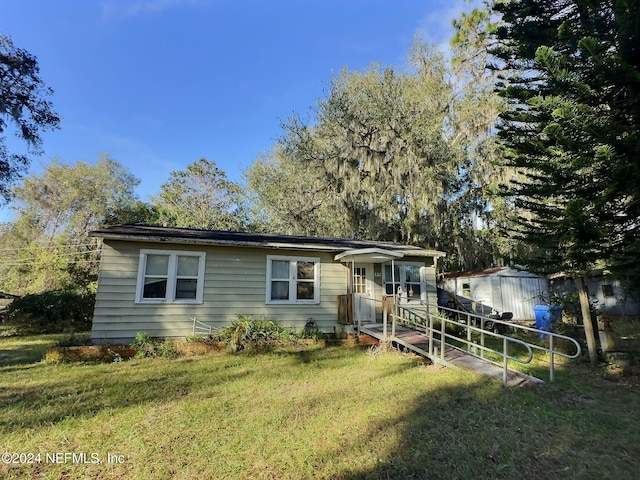 view of front of house featuring a front lawn and a storage shed