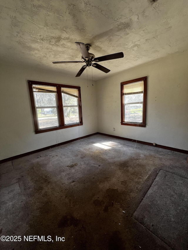 unfurnished room featuring a textured ceiling, carpet, and baseboards