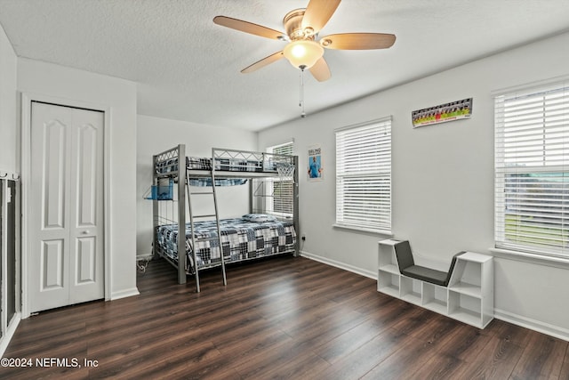 bedroom with dark wood-type flooring, ceiling fan, a closet, and a textured ceiling