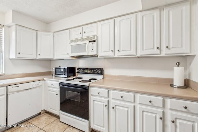 kitchen with a textured ceiling, white cabinetry, light tile patterned flooring, and white appliances