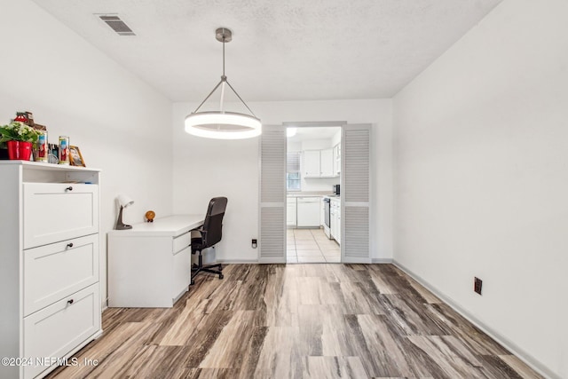 unfurnished office with light hardwood / wood-style flooring and a textured ceiling