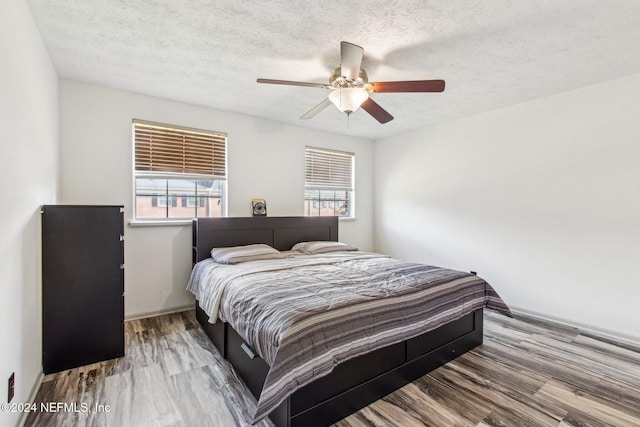 bedroom with a textured ceiling, hardwood / wood-style flooring, and ceiling fan