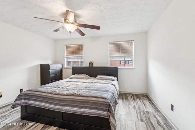 bedroom featuring a textured ceiling, light hardwood / wood-style floors, and ceiling fan