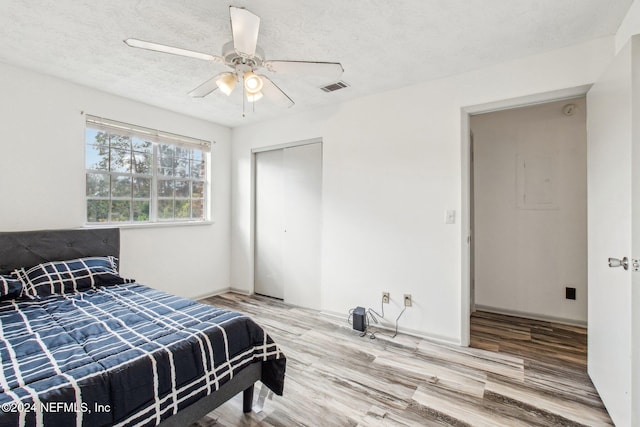 bedroom with hardwood / wood-style floors, ceiling fan, a textured ceiling, and a closet