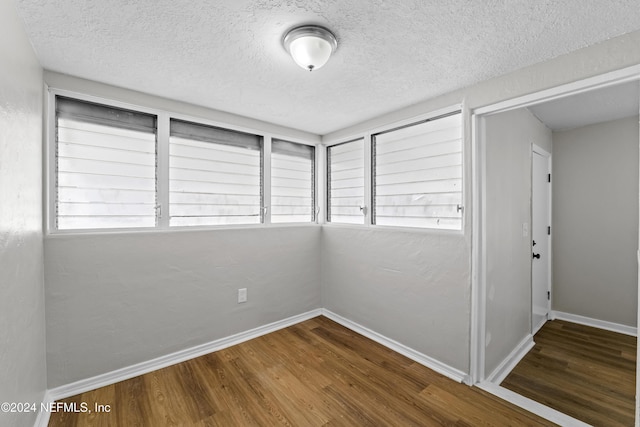 unfurnished room with a textured ceiling and hardwood / wood-style flooring