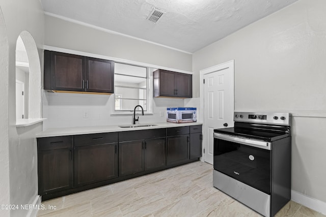 kitchen featuring a textured ceiling, stainless steel electric range, dark brown cabinetry, and sink