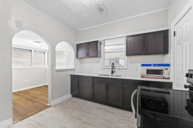 kitchen featuring dark brown cabinets, a textured ceiling, range, and sink