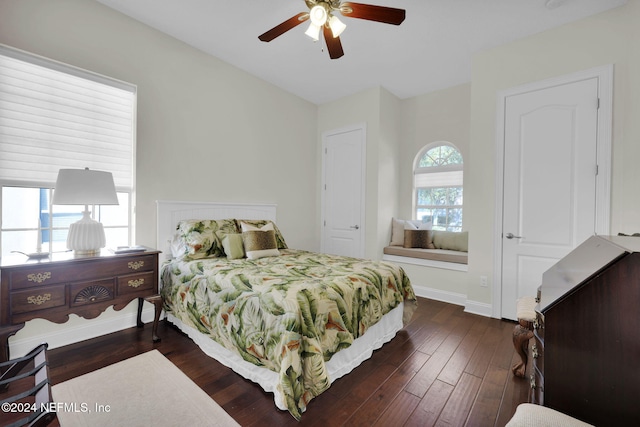 bedroom featuring ceiling fan, dark wood-type flooring, and multiple windows