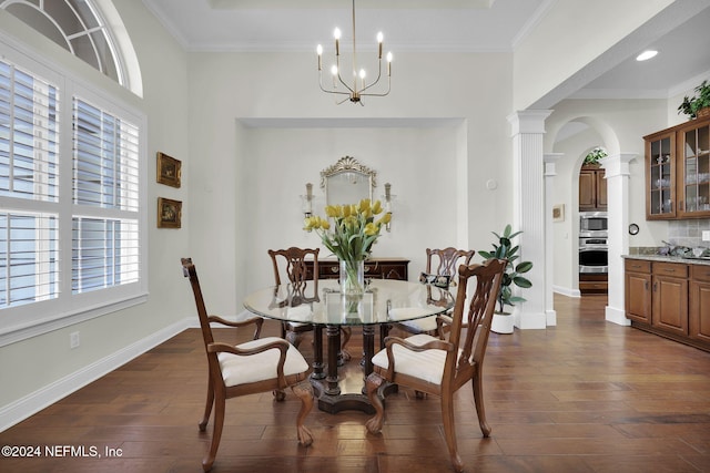 dining space with decorative columns, crown molding, dark wood-type flooring, and an inviting chandelier