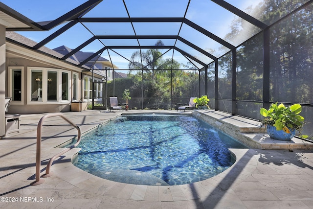 view of pool with pool water feature, glass enclosure, and a patio area