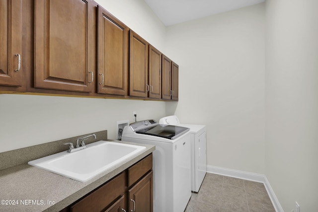 clothes washing area featuring washer and clothes dryer, cabinets, light tile patterned floors, and sink