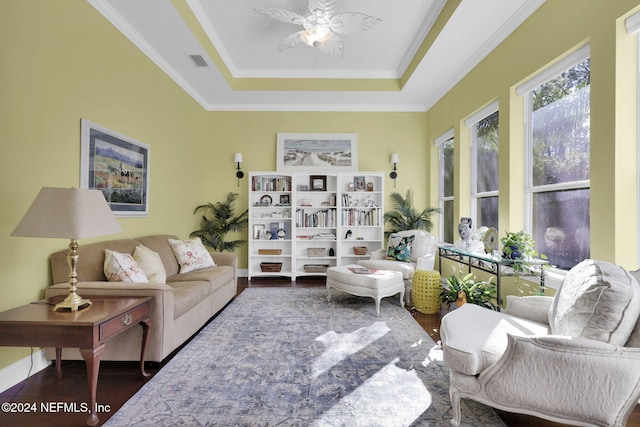 living room with a raised ceiling, ceiling fan, crown molding, and dark hardwood / wood-style floors