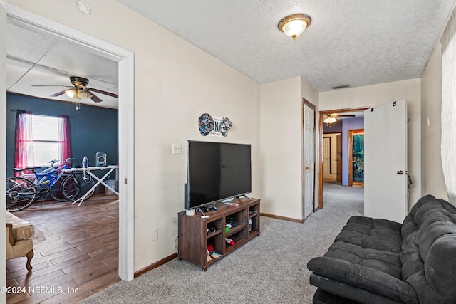 living room with carpet flooring, ceiling fan, and a textured ceiling