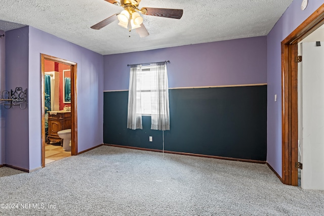 unfurnished bedroom featuring ensuite bathroom, ceiling fan, light carpet, and a textured ceiling