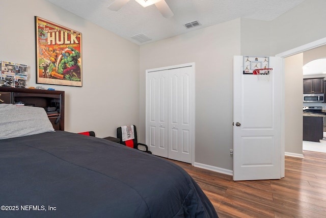 bedroom featuring a textured ceiling, ceiling fan, dark wood-type flooring, and a closet