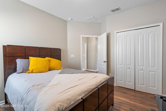 bedroom with a textured ceiling, dark hardwood / wood-style flooring, and a closet