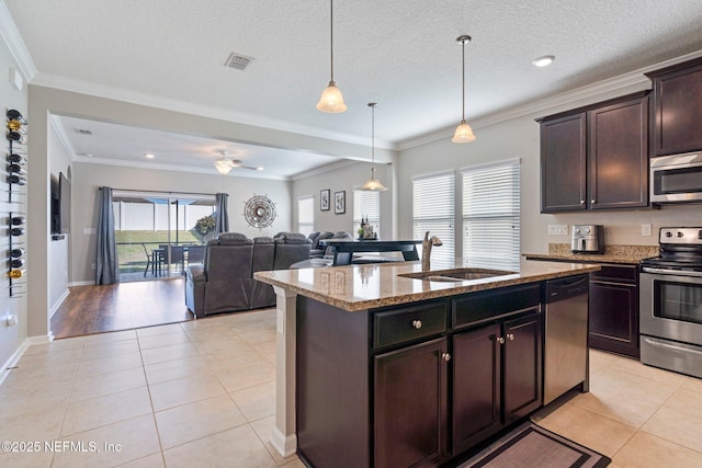 kitchen with sink, light tile patterned floors, appliances with stainless steel finishes, light stone counters, and dark brown cabinetry