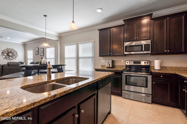 kitchen with light stone countertops, appliances with stainless steel finishes, dark brown cabinetry, sink, and decorative light fixtures