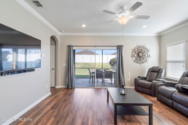 living room with a textured ceiling, ceiling fan, dark hardwood / wood-style flooring, and crown molding