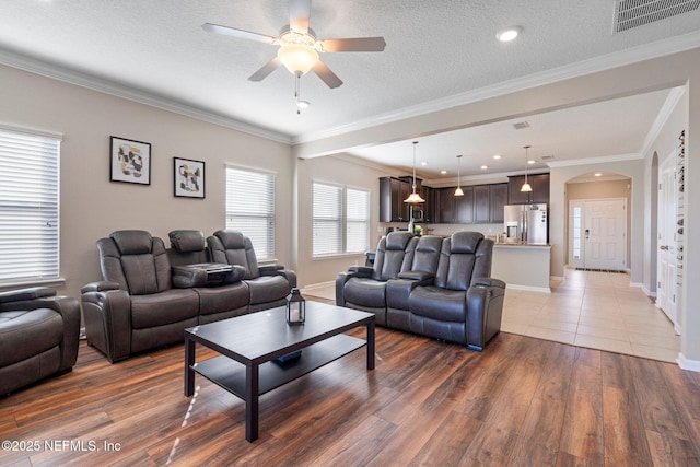 living room with a textured ceiling, dark hardwood / wood-style flooring, ceiling fan, and crown molding