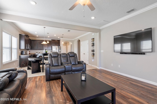 living room featuring crown molding, ceiling fan, dark wood-type flooring, and a textured ceiling