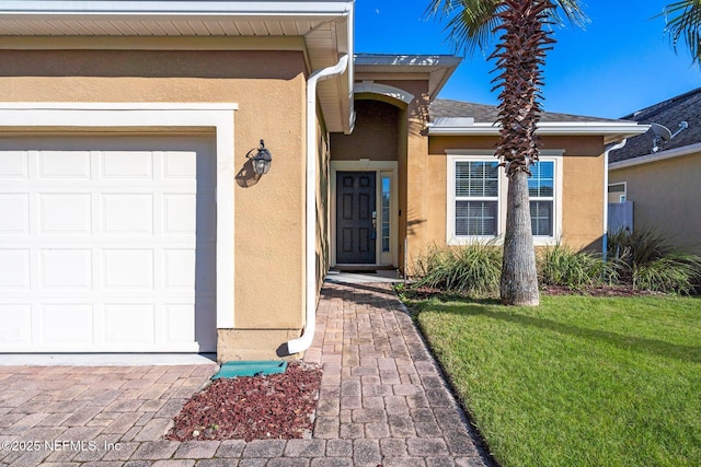 view of exterior entry featuring a lawn and a garage