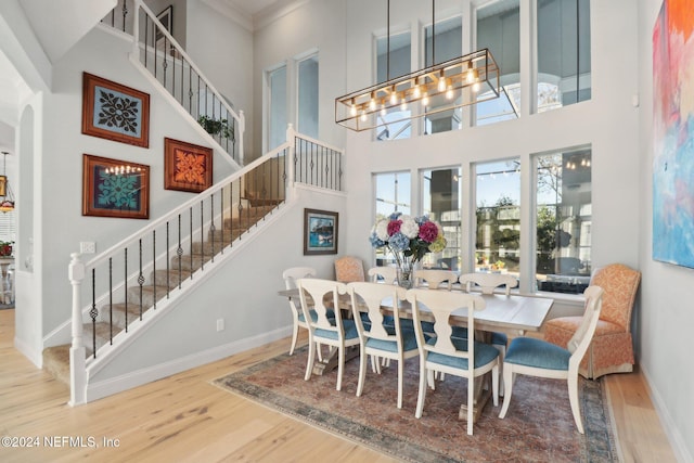 dining space with hardwood / wood-style flooring, a towering ceiling, and a chandelier