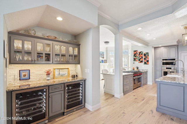 bar featuring wine cooler, gray cabinets, and appliances with stainless steel finishes