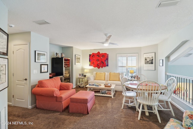 living room featuring ceiling fan, dark carpet, and a textured ceiling