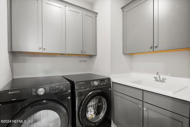 washroom with cabinets, separate washer and dryer, and sink