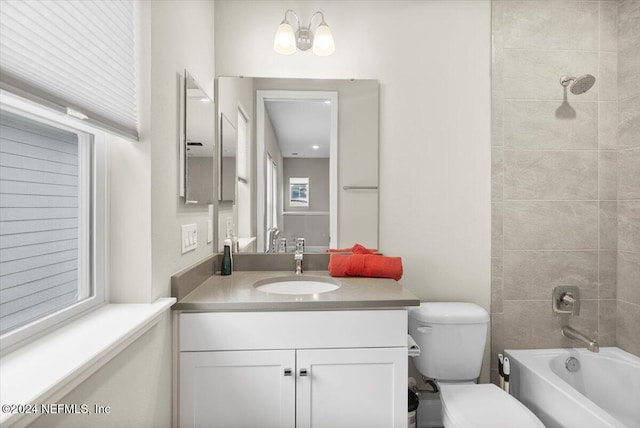 full bathroom with tiled shower / bath, vanity, and toilet