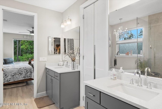 bathroom featuring vanity, ceiling fan with notable chandelier, a healthy amount of sunlight, and hardwood / wood-style floors