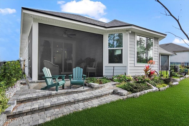 back of property with ceiling fan, a patio, a sunroom, and a lawn