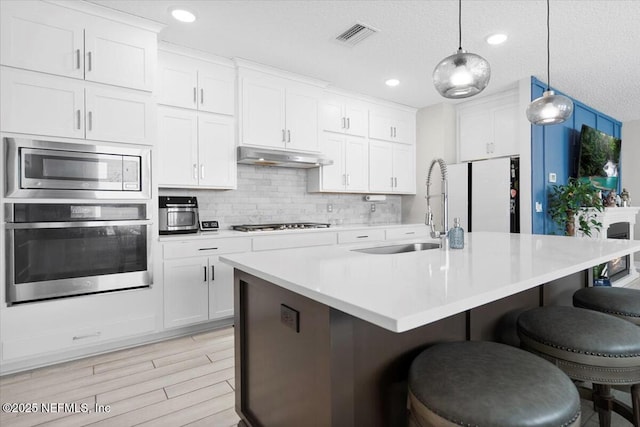 kitchen featuring pendant lighting, white cabinetry, stainless steel appliances, and a breakfast bar area