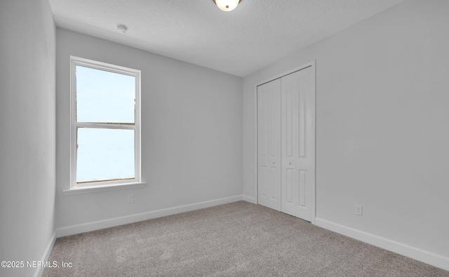 unfurnished bedroom with light colored carpet, a textured ceiling, and a closet