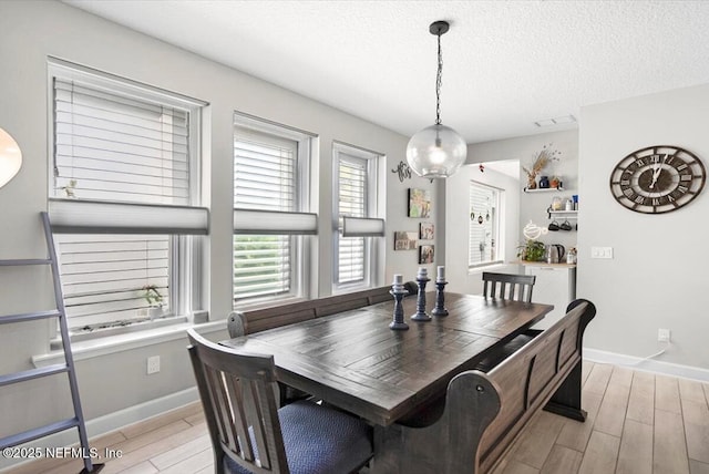 dining area with wood tiled floor, visible vents, a textured ceiling, and baseboards