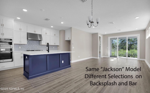 kitchen featuring light wood-style floors, white cabinets, light countertops, and under cabinet range hood