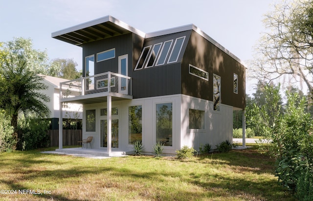 rear view of house with a lawn and a balcony