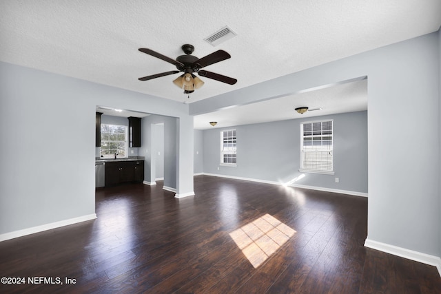 unfurnished living room featuring ceiling fan, a textured ceiling, and dark hardwood / wood-style floors