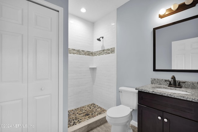 bathroom with vanity, toilet, and tiled shower