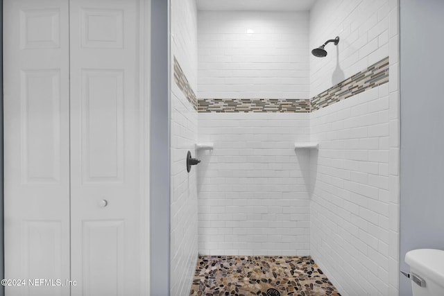 bathroom with toilet and a tile shower