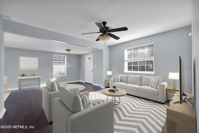 living room featuring ceiling fan, dark wood-type flooring, and a textured ceiling