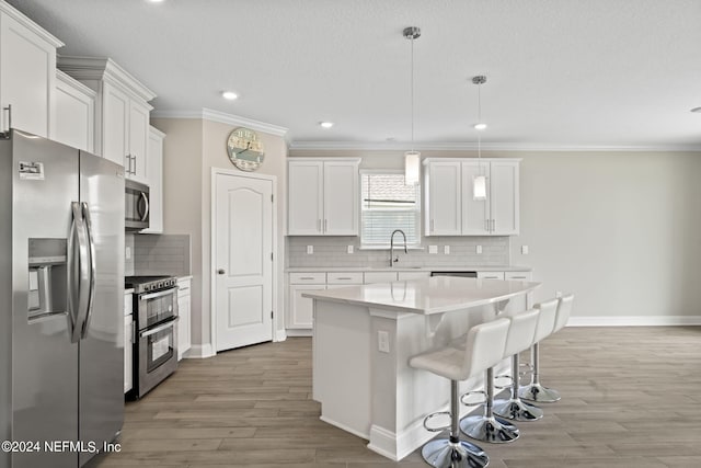 kitchen featuring hardwood / wood-style floors, hanging light fixtures, a kitchen island, white cabinetry, and stainless steel appliances