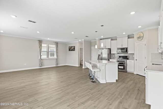 kitchen with light wood-type flooring, appliances with stainless steel finishes, a center island, and white cabinetry