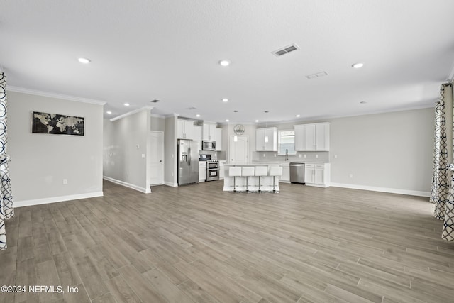 unfurnished living room with crown molding and light hardwood / wood-style floors