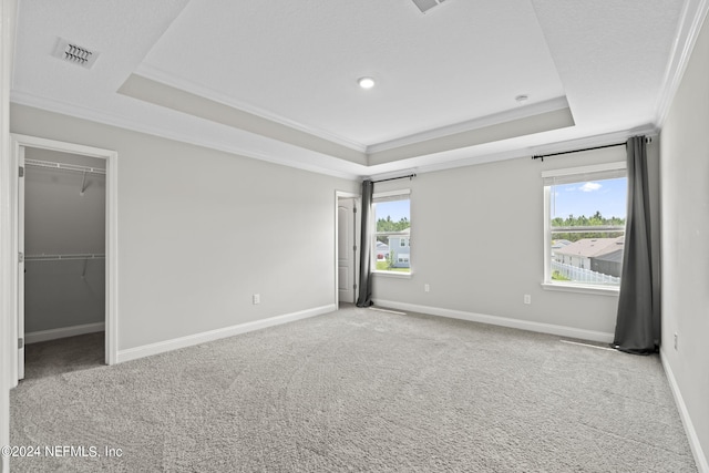 unfurnished bedroom featuring a raised ceiling, multiple windows, crown molding, and light carpet