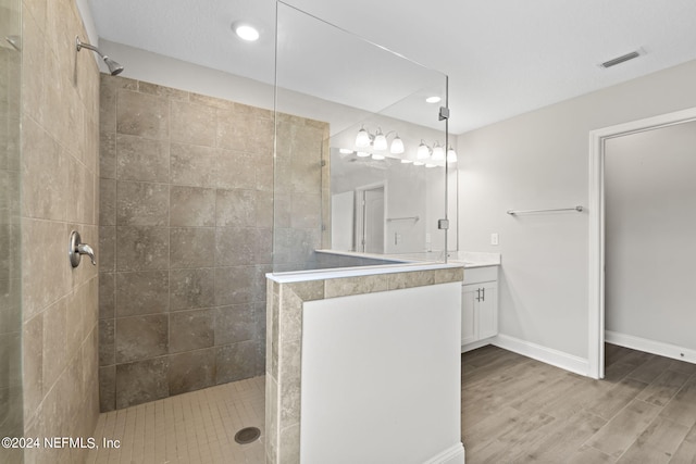 bathroom featuring hardwood / wood-style flooring, vanity, and tiled shower